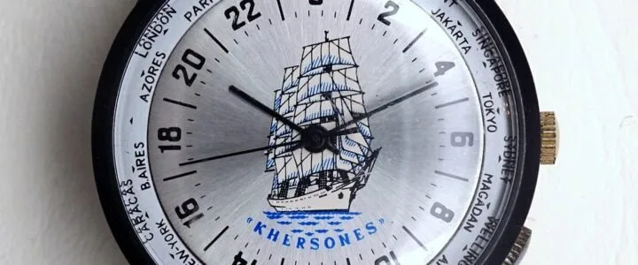 Close-up of a Khersones wristwatch showing different world cities and a ship illustration on the dial.