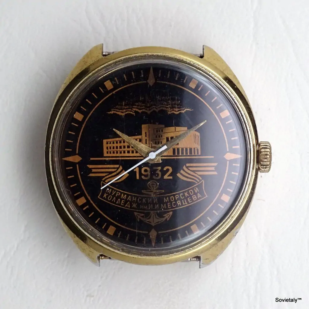 Primo piano di un orologio con quadrante nero e dettagli dorati, recante la scritta in cirillico "1932" e "МУРМАНСКИЙ МОРСКОЙ КОЛЛЕДЖ ИМ. И. МЕСЯЦЕВА". Proprietà di Sovietaly.