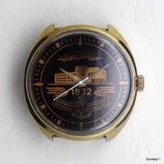 Primo piano di un orologio con quadrante nero e dettagli dorati, recante la scritta in cirillico "1932" e "МУРМАНСКИЙ МОРСКОЙ КОЛЛЕДЖ ИМ. И. МЕСЯЦЕВА". Proprietà di Sovietaly.
